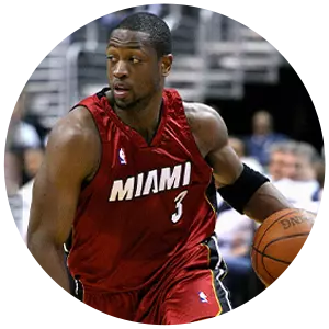 Dwyane Wade, wearing a red Miami Heat jersey with the number 3, is dribbling a basketball on an indoor court, looking to his left during a game.