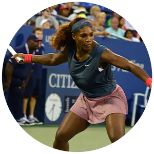 Tennis player Serena Williams, wearing a sleeveless top and skirt, prepares to hit a forehand shot on a hard court during a match, with a crowd in the background.
